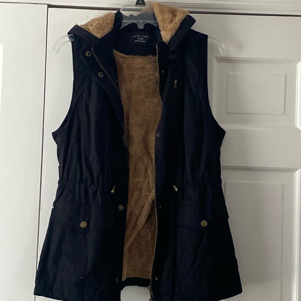 Black vest with brown fur . Hood